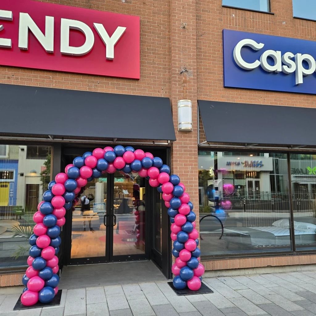 Pink and navy balloon arch around a storefront door