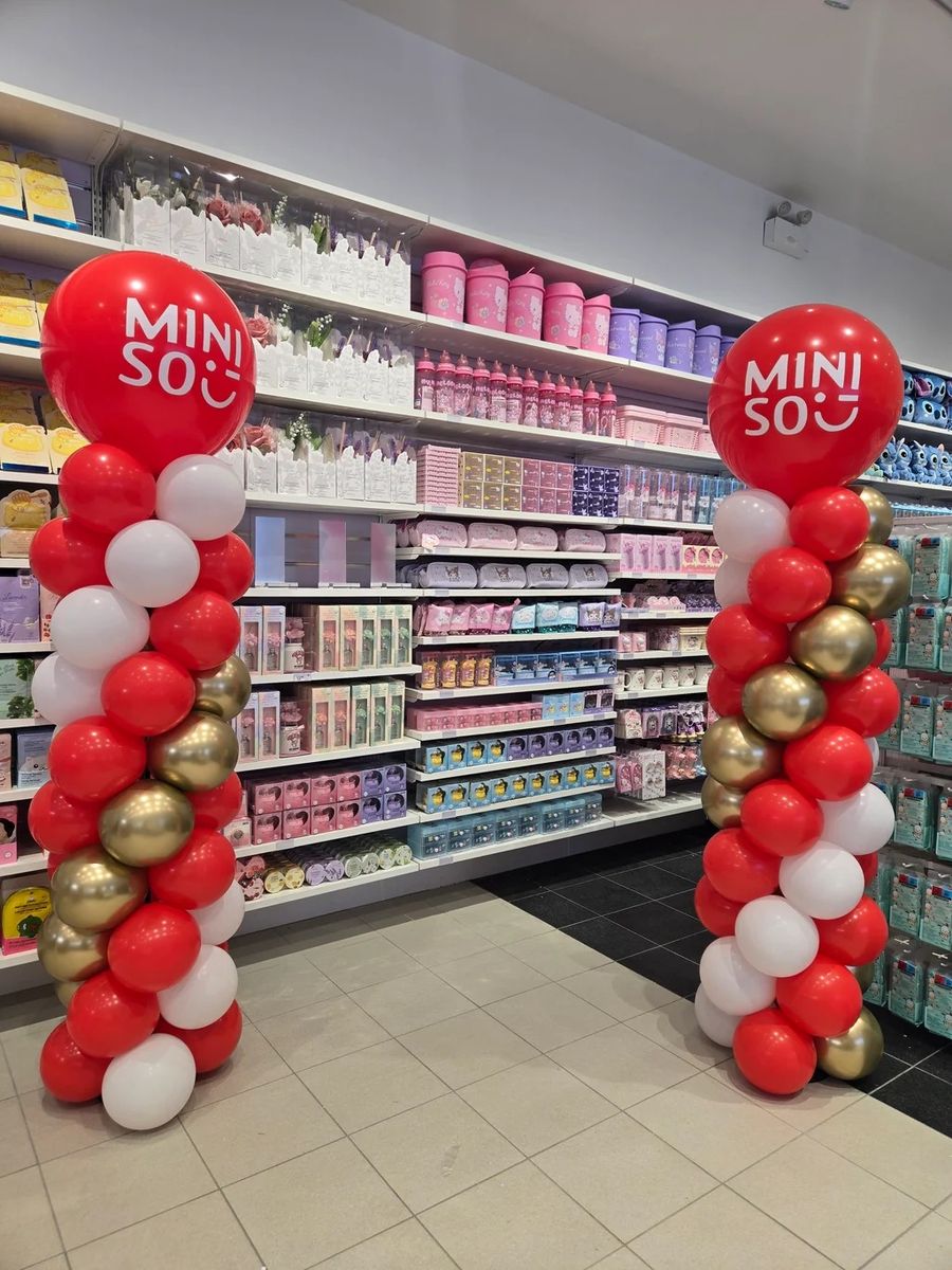 Red, white and gold columns with Miniso logo toppers inside a store