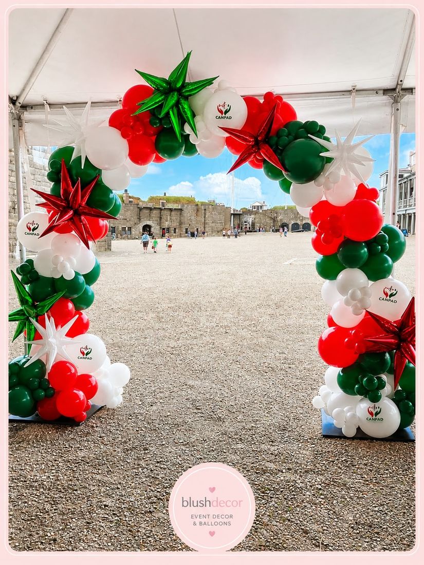 Red, green and white holiday arch with CANPAD logo balloons and foil starbursts