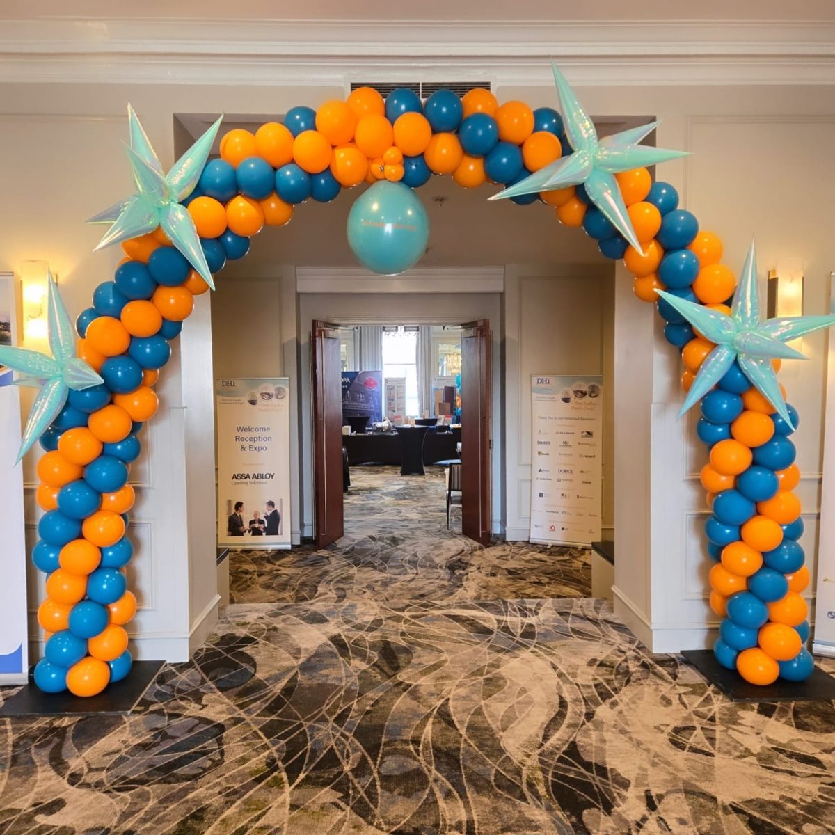 Orange and teal spiral arch with iridescent starbursts at a hotel conference entrance