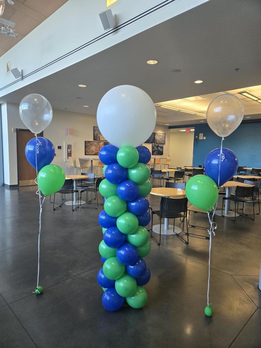 Blue and green spiral column with a white topper between helium bouquets