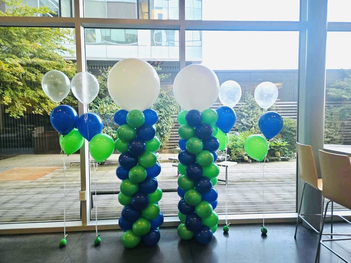 Blue and green spiral column pair with white toppers and helium bouquets by a window