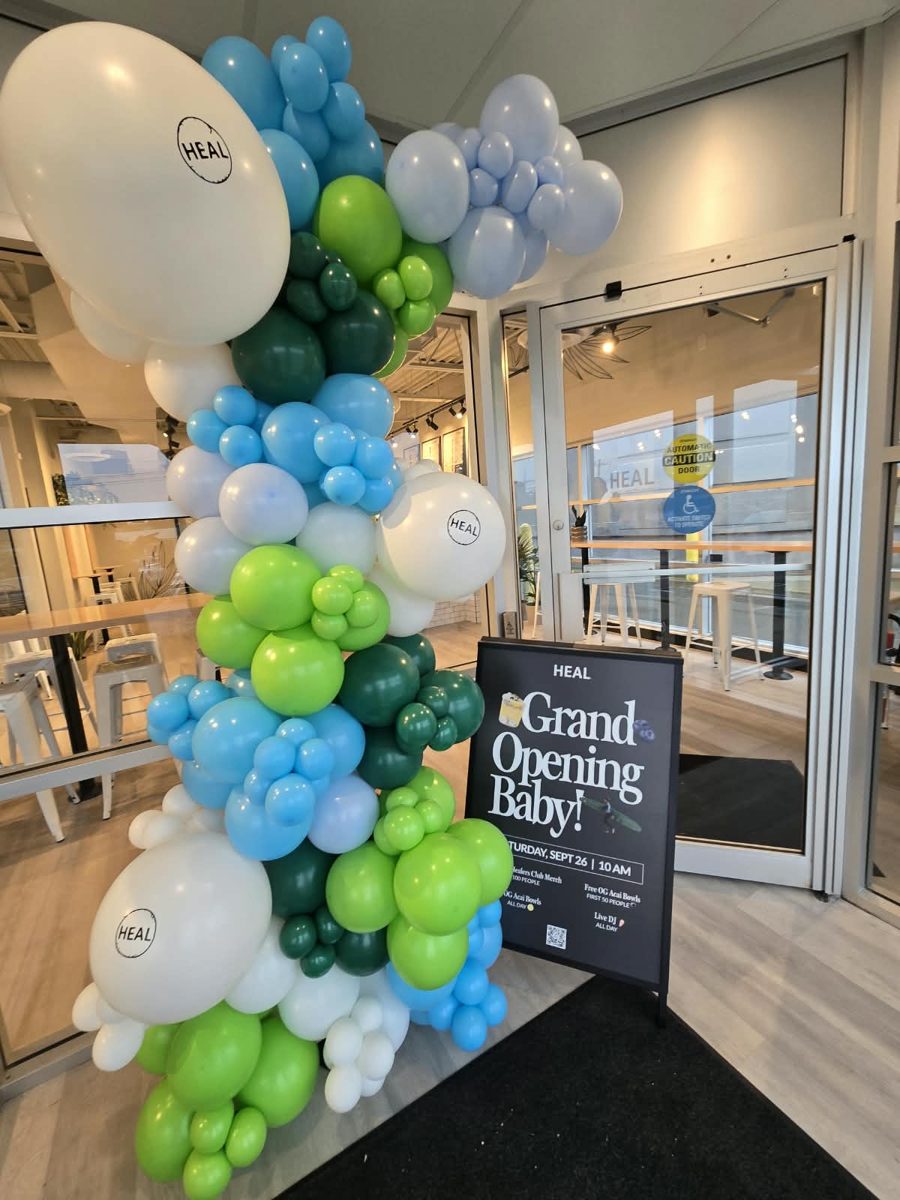 Blue, green and white organic garland with HEAL logo balloons at a grand opening entrance