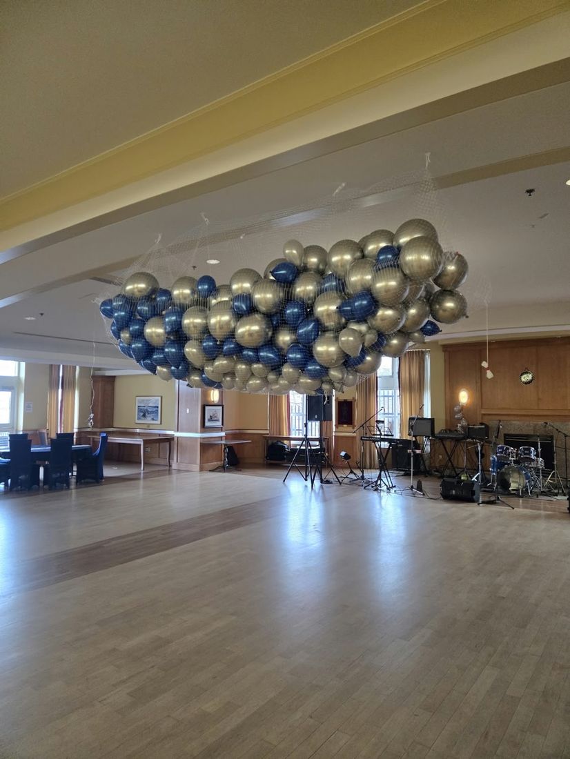 Gold and navy balloons packed into a drop net above a dance floor